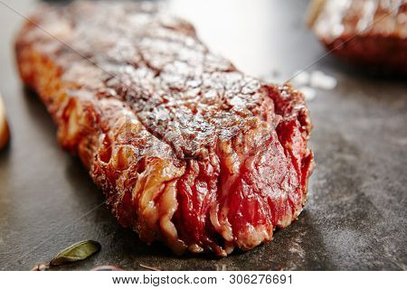 Hot Grilled Whole Tri-tip Steak on Black Stone Background. Fresh Juicy Medium Rare Beef Grillsteak. Barbecue Meat Close Up