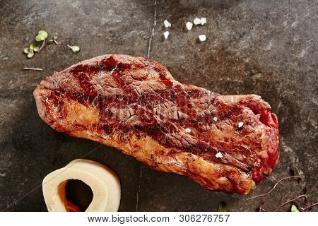 Hot Grilled Whole Tri-tip Steak on Black Stone Background. Fresh Juicy Medium Rare Beef Grillsteak. Barbecue Meat Top View Close Up