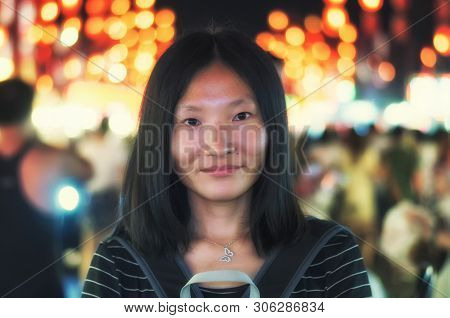 A Chinese Woman On A Brightly Lit Street In Luoyang China In Henan Province At Night.
