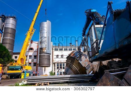 Crane Is Bringing Down Heavy Metal Silo In Industrial Complex.