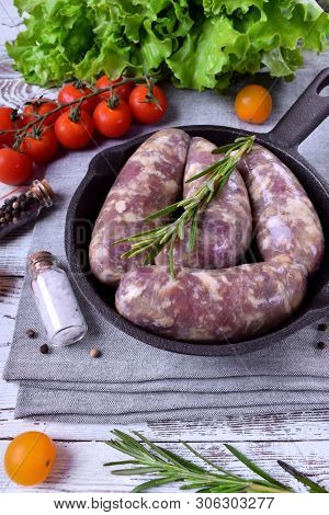 Raw Meat Sausages In A Natural Shell In A Cast Iron Pan Prepared For Grilling