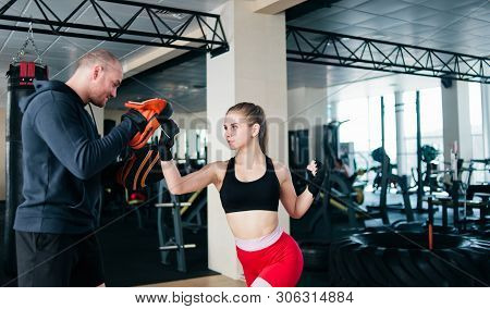 Fit Blonde Woman Training  Punch With Man Trainer.  At The Gym. Couple Exercising Punching