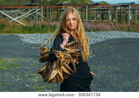 Girl In Black Dress With Bundle Of Dried Fish Heads, Lofoten Islands, Norway