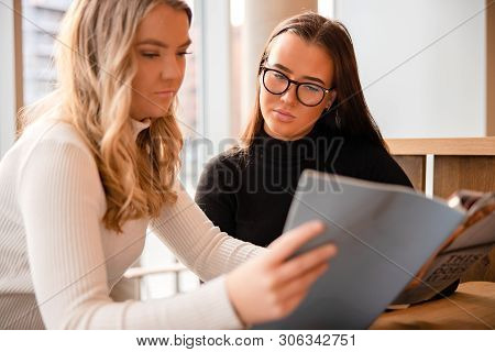 Close-up Of Serious Young Somen Discussing Over Publication In Cafe