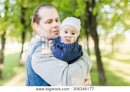 Portrait Of The Beautiful Astonished Baby Looking Into The Lens At The Hands Of The Young Loving Dad