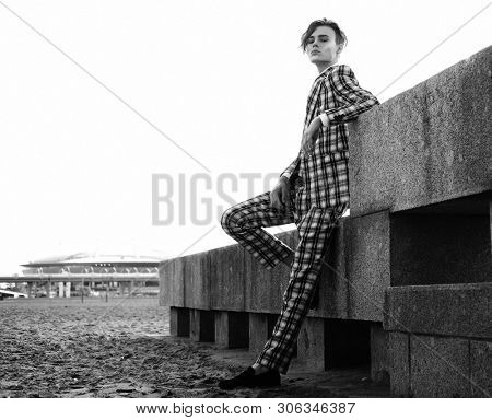 handsome fashion male model dressed in elegant suit posing outdooe. Long haired Metrosexual. Black and white picture.