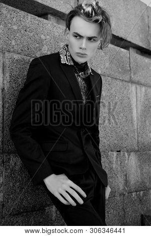 handsome fashion male model dressed in elegant suit posing outdooe. Long haired Metrosexual. Black and white picture.