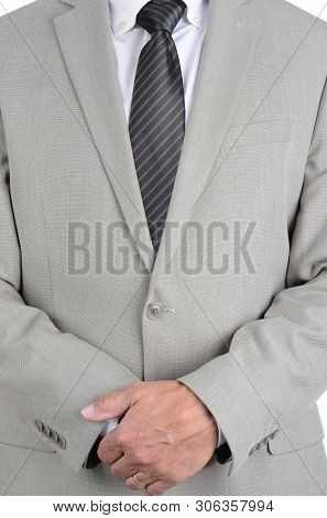 Closeup businessman in a light gray suit and gray striped tie with hands clasped in front, torso only man is unrecognizable. 