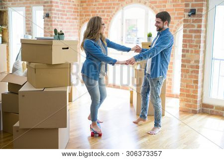 Young couple moving to a new home, having fun riding a skateboar