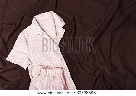 Pink Pajamas For Girls On Chocolade Colored Sheet. Soft Cotton Nightwear. Copy Space. Top View. Flat
