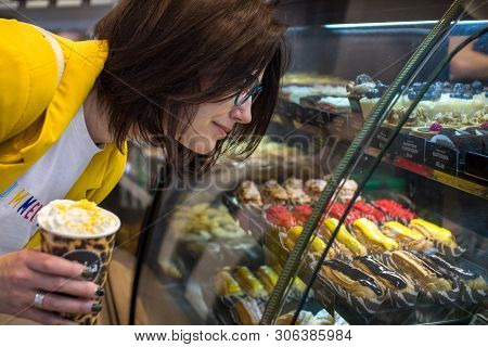 The Concept Of Diet And Sweet. Sweet Tooth Girl In A Candy Store Looking At A Glass Window With Colo