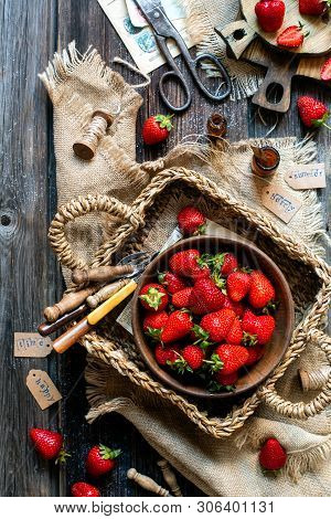 Overhead Shot Of Tasty Ripe Strawberries In Wooden Bowl Stands In Wicker Strawy Basket On Rustic Tab