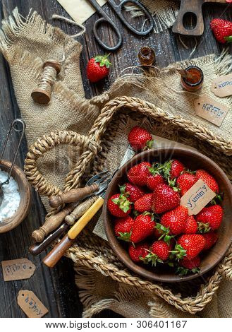 Overhead Shot Of Tasty Ripe Strawberries In Wooden Bowl Stands In Wicker Strawy Basket On Rustic Tab