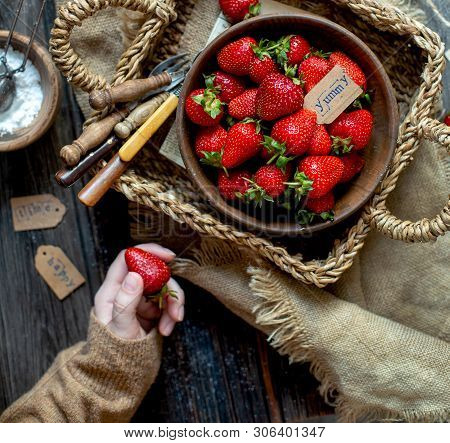 Overhead Shot Of Tasty Ripe Strawberries In Wooden Bowl Stands In Wicker Strawy Basket On Rustic Tab