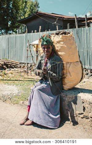 Debre Libanos, Ethiopia, April 19.2019, Ethiopian Woman Rests, Carrying A Sack Of Charcoal On Her Ba
