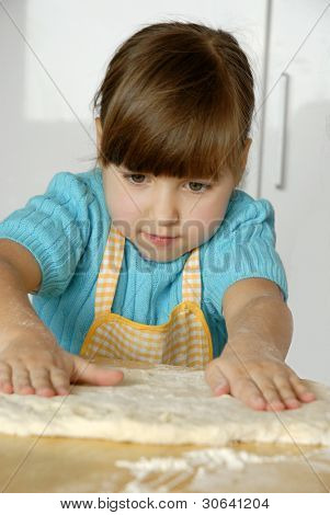 Bambina cucinare una pizza in una cucina.Ragazzino in una cucina.