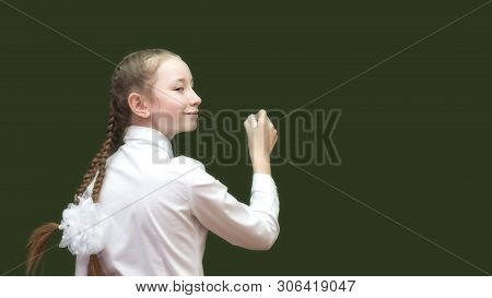 Schoolgirl Teen With Chalk On  Blackboard Writes The Solution To The Problem A Girl Of 10-12 Years O