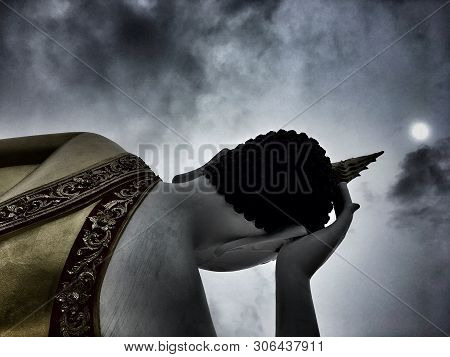 Backside Of Buddha Statue Lying By Using Hand To Hold The Head Under The Sun. Dark And Noise Image A