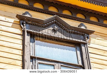 Russian Traditional Wooden Architecture. Facade Of An Old House Decorated With Wooden Carvings, Plat