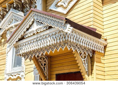 Russian Traditional Wooden Architecture. Facade Of An Old House Decorated With Wooden Carvings, Plat