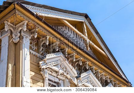 Russian Traditional Wooden Architecture. Facade Of An Old House Decorated With Wooden Carvings, Plat