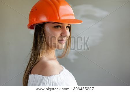 Charming Woman Begins To Make Repairs In The House On Her Orange Construction Helmet
