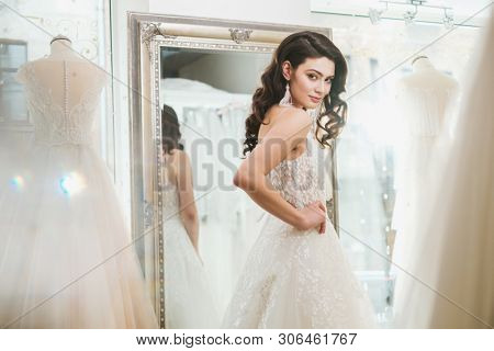 Beautifu bride choosing wedding dress in a wedding salon