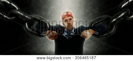 Confident and angry business man breaking chain. Business concept of liberation from credit slavery