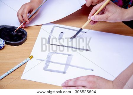 Womans Hands Writing Chinese Hieroglyph. Female Hand Holding A Writing Brush Calligraphy Chinese Cha
