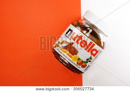 Kyiv, Ukraine - May 27, 2019: Nutella introduced to the market in 1964 by Italian company Ferrero. Nutella hazelnut on white and red background
