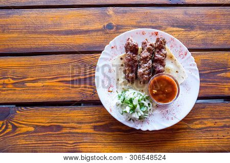 Portion Luleh Kebab On A Plate. Appetizing Dish On The Wooden Brown Table.