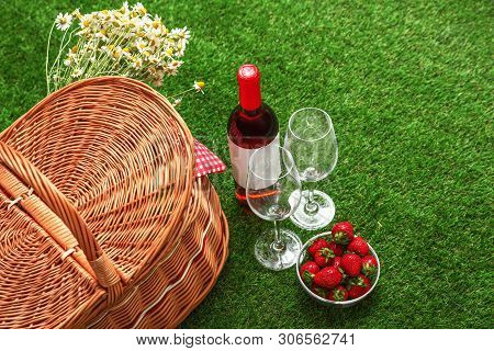 Picnic Basket With Wine And Bowl Of Strawberries On Grass