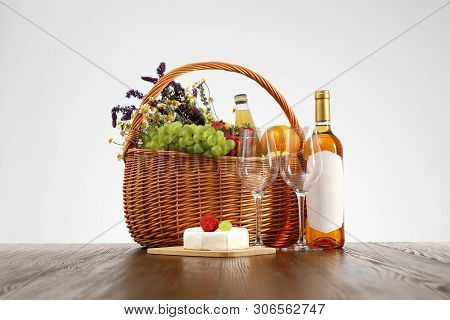 Picnic Basket With Wine And Products On Wooden Table Against White Background
