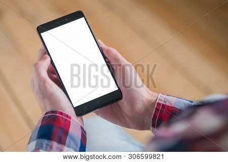 Mockup Image: Man Looking At Black Smartphone With White Blank Screen. Close Up View Of Man Hands Wi
