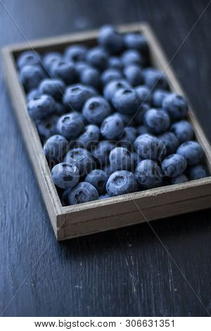 A Tasty And Healthy Snack: A Box Of Juicy And Sweet Blueberries On The Black Background.