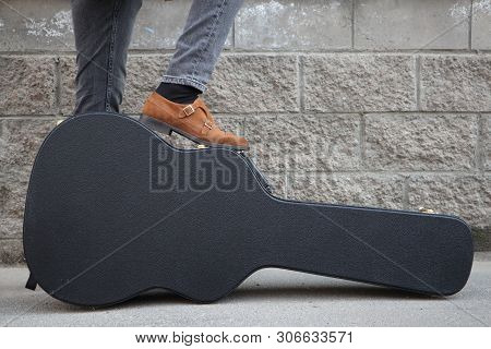 Man Put His Foot On A Hard Guitar Case. Hard Case For Electric Guitar. Man Dressed In Jeans Holding 