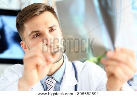 Portrait Of Serious Physician Examining Attentively Sciagram. Concentrated Doc Holding Sciagraph And