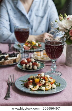 A Gourmet Lunch For Two: Two Plates Of Tomato Salad With Mozzarella, Aragula And Pumpkin Seeds, A Pl