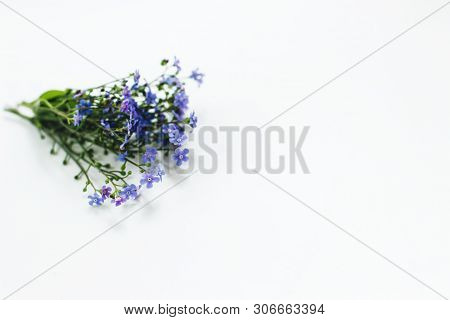 A Small Cute Bouquet Of Blue Forget-me-nots Lies On A White Table. Selective Focus. There Is Room Fo