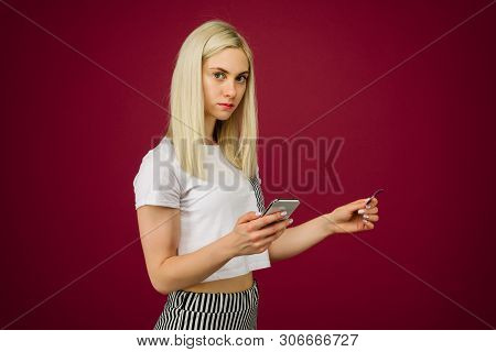 A Young Woman Holds A Smartphone And A Credit Card In Her Hands. Problems With A Bank Card, Because 