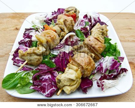 Chicken Skewers With Lettuce And Chicory On A White Plate, Wooden Table