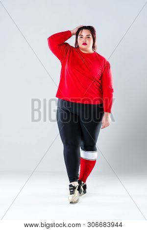 Plus Size Model In Sportswear, Fat Woman Doing Workout On Gray Background, Healthy Lifestyle Concept