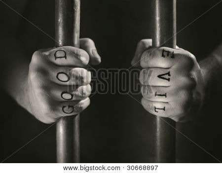 Mann mit (falschen) gut und Böse Tätowierungen hinter Gittern.
