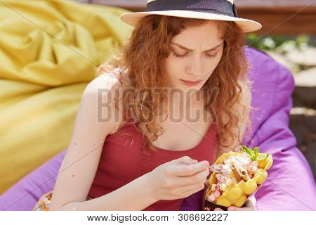 Outdoor Shot Of Caucasian Charming Woman Eating Healthy Enjoying Frozen Treat Snack In Summer Park, 