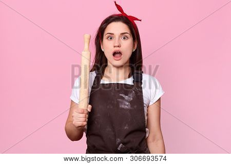 Close Up Portrait Of Emotional Brunette Housewife Opens Her Mouth Widely With Shock, Holding Wooden 