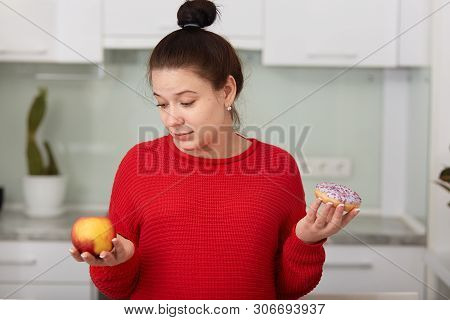 Portrait Of Pragnant Woman Deciding To Choose Healthy Or Unhealthy Food, Posing Isolated On White Ki