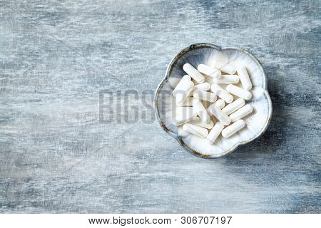 Theanine Capsules. Dietary Supplement.   Rustic Wooden Background. Top View. Copy Space.
