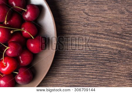 Red Cherries On A Brown Plate On A Wooden Table. Summer Food, Healthy Eating. Organic, Vegetarian, V