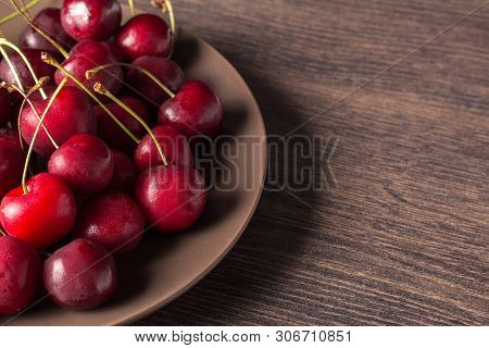 Fresh Cherries On A Brown Plate On A Wooden Table. Summer Food, Healthy Eating. Organic, Vegetarian,