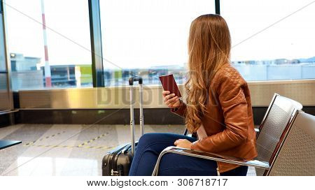 Beautiful Young Woman Looking Out Window While Waiting Boarding On Aircraft With Passport In Her Han